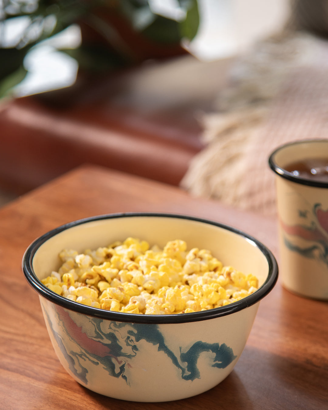 Popcorn served in candy swirl mixing bowl for movie night with coffee in tumbler beside