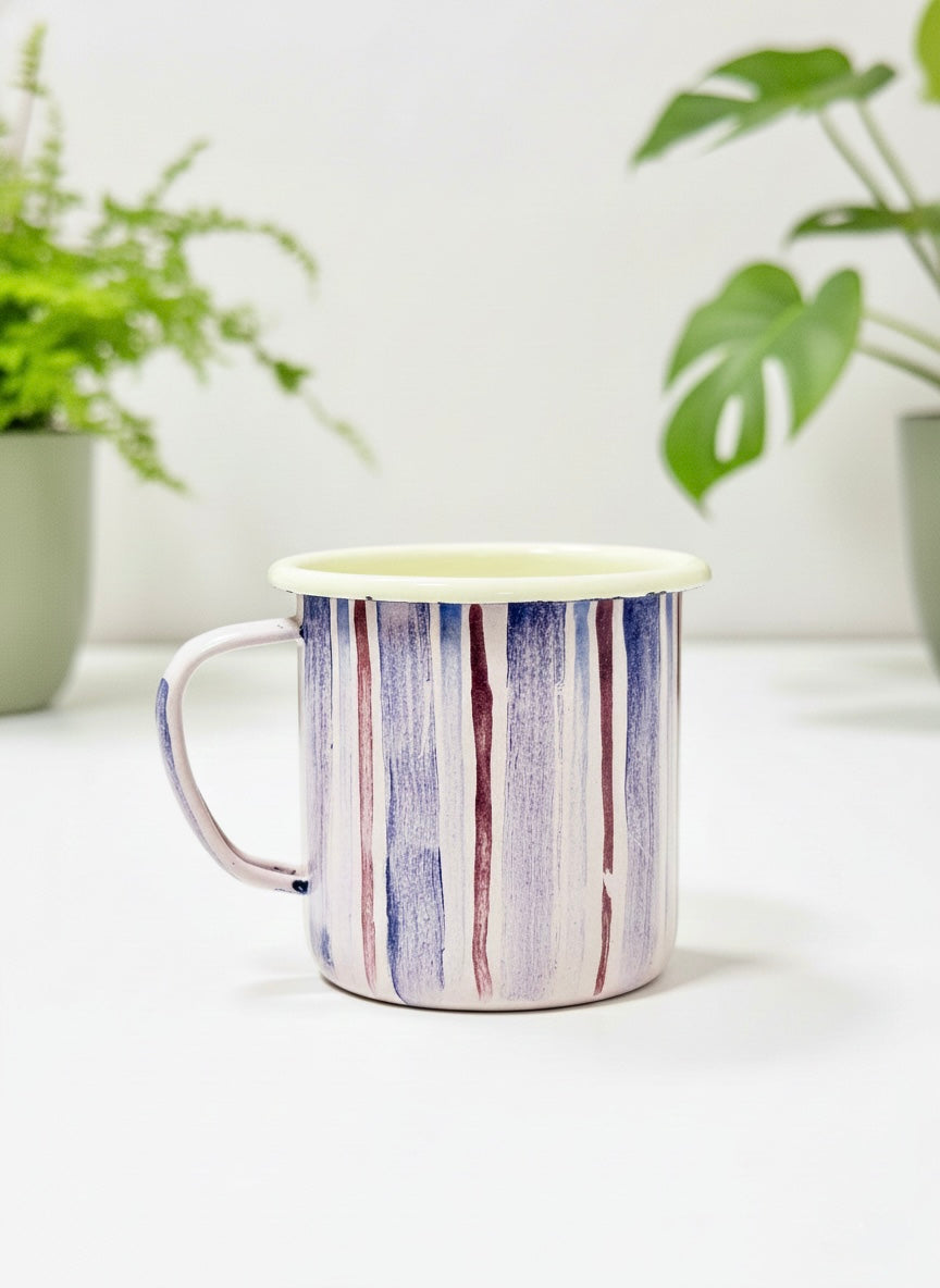 Lilac Striped enamel coffee mug on a white surface with plants in the background