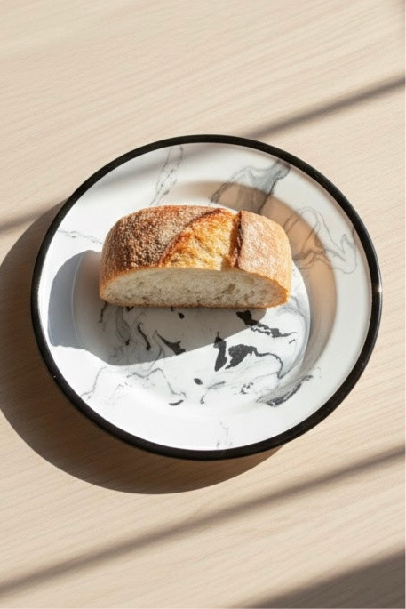 Top view of noir white marbling enamel dinner plate with minimal food styling and visible pattern.