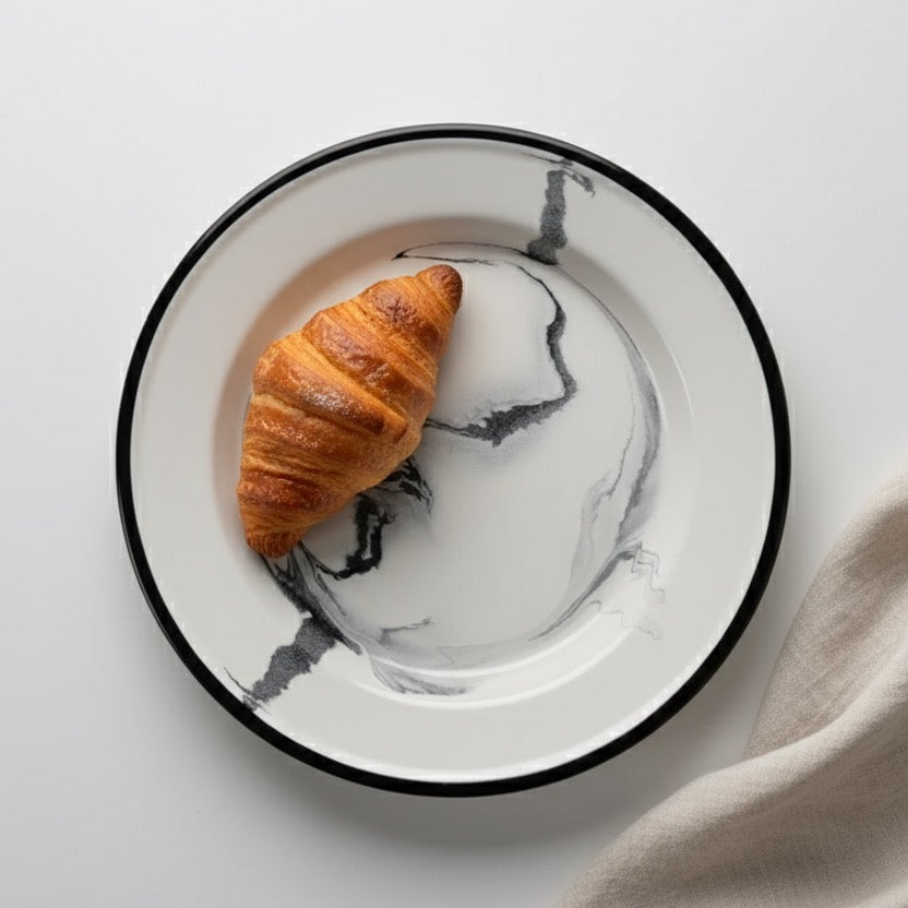 Marble-patterned plate with a croissant on a light gray surface