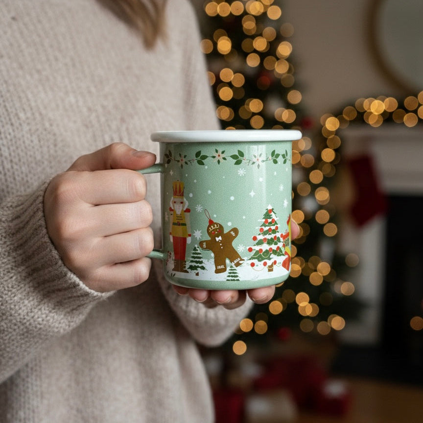 Person holding a Christmas nutcracker enamel coffee mug with a blurred festive background