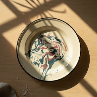 Top view of candy swirl marbling enamel dinner plate with minimal food styling and visible pattern.